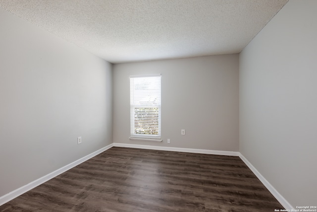 unfurnished room with a textured ceiling and dark hardwood / wood-style floors