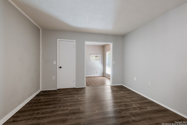 unfurnished room featuring a textured ceiling and dark hardwood / wood-style floors