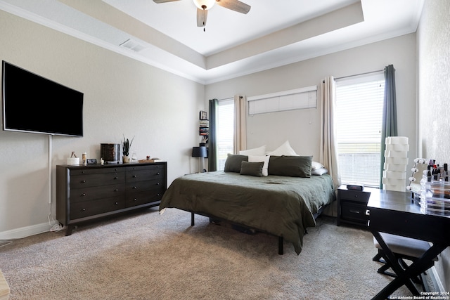 bedroom with ceiling fan, a tray ceiling, light carpet, and crown molding