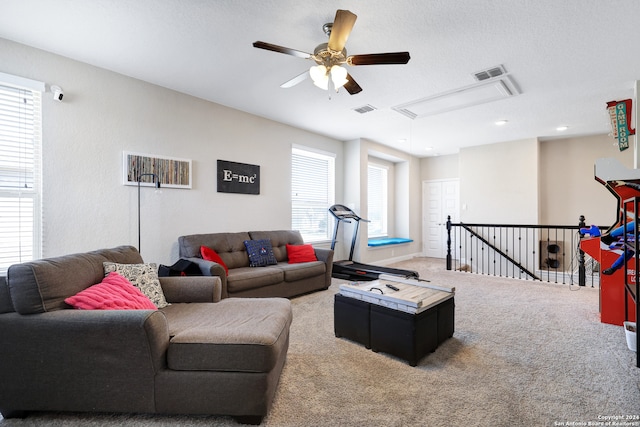 living room featuring ceiling fan, a textured ceiling, carpet flooring, and a healthy amount of sunlight