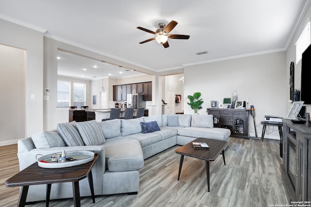 living room featuring crown molding, light hardwood / wood-style floors, and ceiling fan