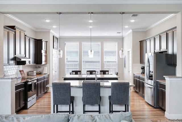 kitchen featuring light hardwood / wood-style flooring, appliances with stainless steel finishes, decorative light fixtures, and tasteful backsplash