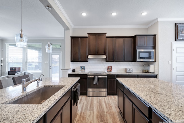 kitchen with pendant lighting, ornamental molding, appliances with stainless steel finishes, and sink