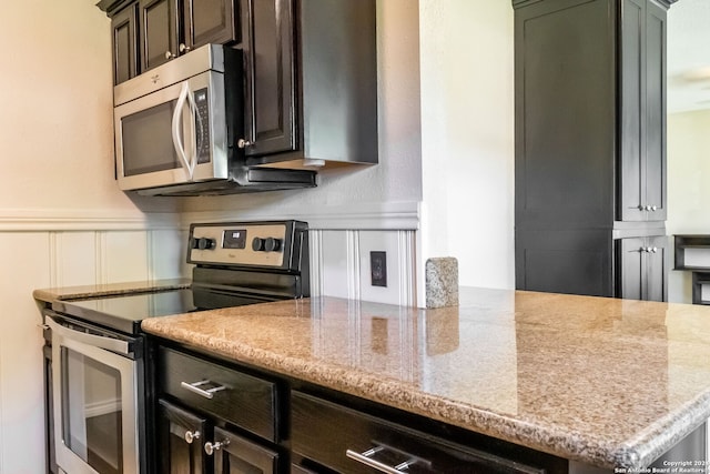 kitchen featuring dark brown cabinetry, kitchen peninsula, light stone countertops, and stainless steel appliances