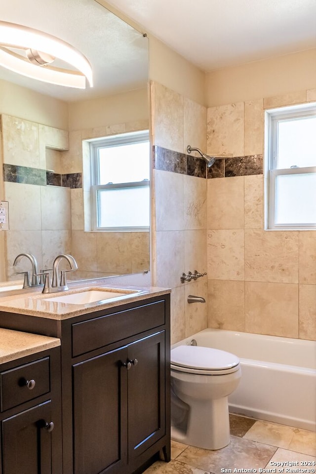 full bathroom with tile walls, tiled shower / bath combo, vanity, and toilet