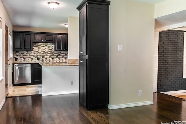 kitchen with sink, tasteful backsplash, dishwasher, light stone countertops, and hardwood / wood-style floors