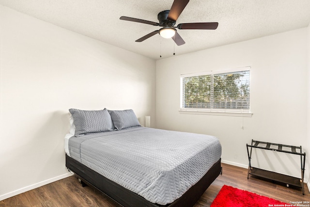 bedroom with ceiling fan, dark hardwood / wood-style floors, and a textured ceiling