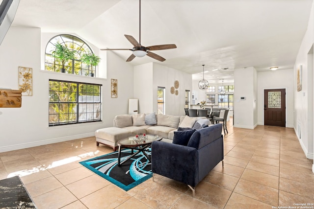 living room with light tile patterned flooring, ceiling fan with notable chandelier, and high vaulted ceiling