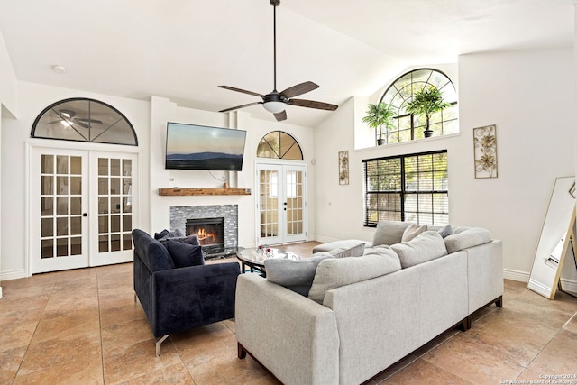 living room featuring lofted ceiling, ceiling fan, french doors, and a stone fireplace