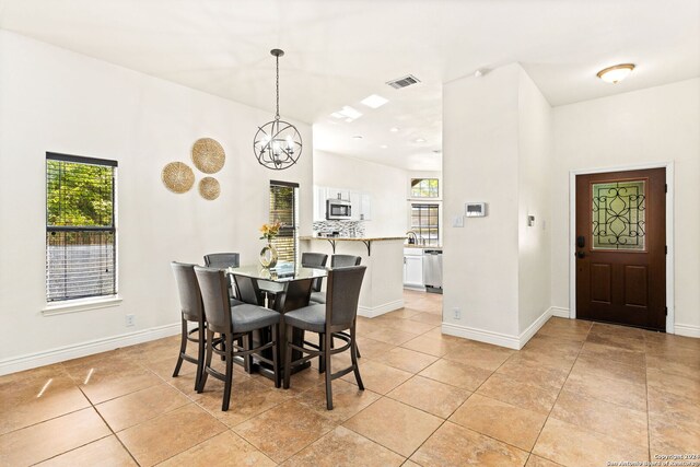 tiled dining room featuring an inviting chandelier, a healthy amount of sunlight, and sink