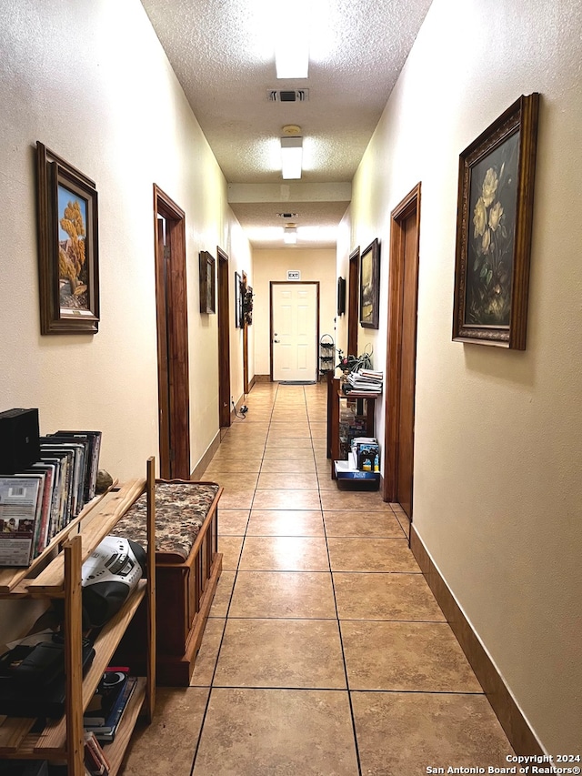 corridor with a textured ceiling and light tile patterned floors