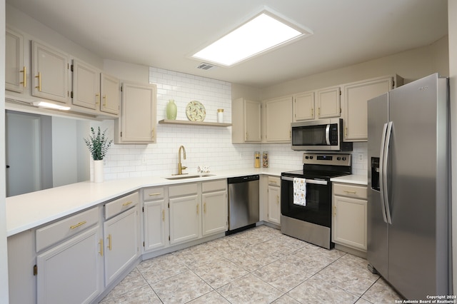 kitchen with appliances with stainless steel finishes, decorative backsplash, sink, and light tile patterned floors