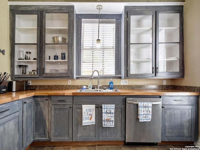 bar featuring dishwasher, decorative light fixtures, sink, and wooden counters