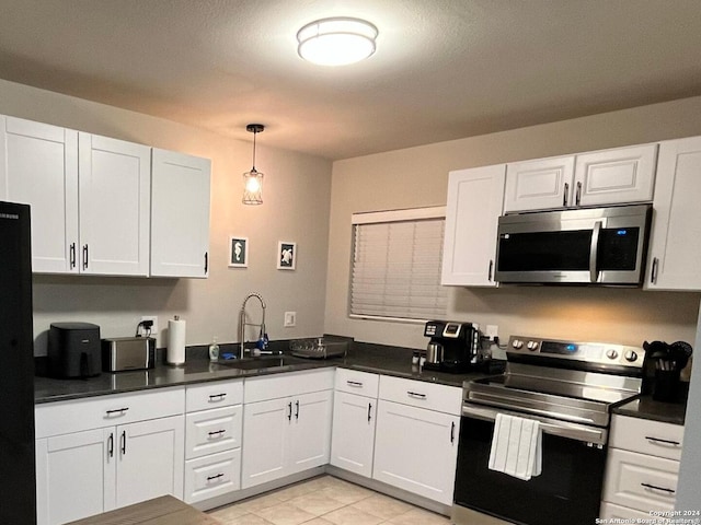 kitchen featuring hanging light fixtures, light tile patterned flooring, white cabinets, stainless steel appliances, and sink