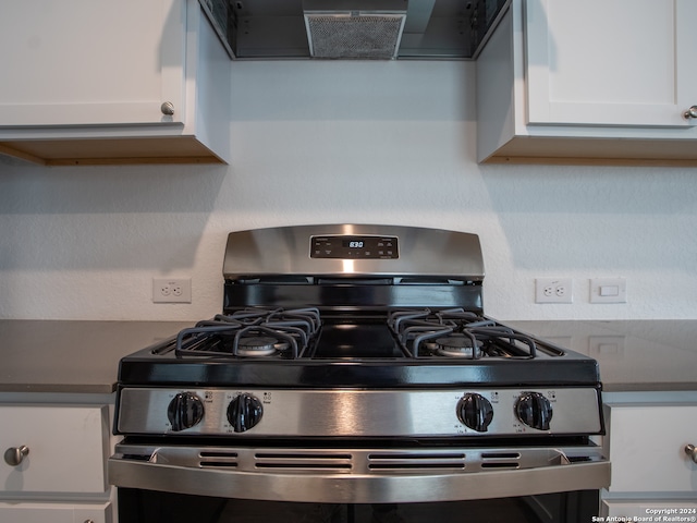 interior details with white cabinetry, extractor fan, and stainless steel gas range