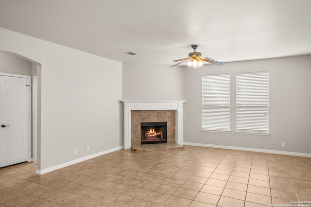 unfurnished living room with ceiling fan, a fireplace, and light tile patterned floors