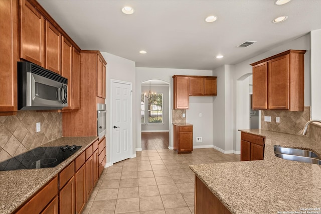 kitchen featuring light stone counters, tasteful backsplash, light tile patterned flooring, sink, and appliances with stainless steel finishes