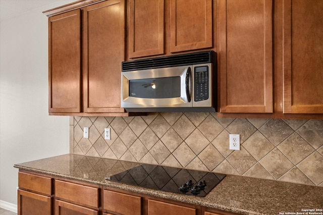 kitchen with dark stone countertops, black electric cooktop, and tasteful backsplash