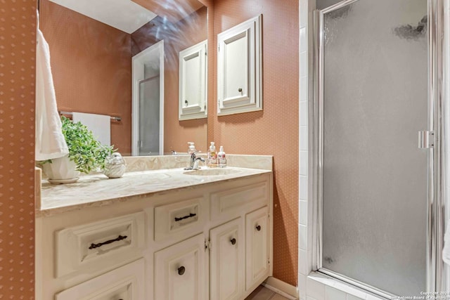 bathroom with a shower with shower door and vanity