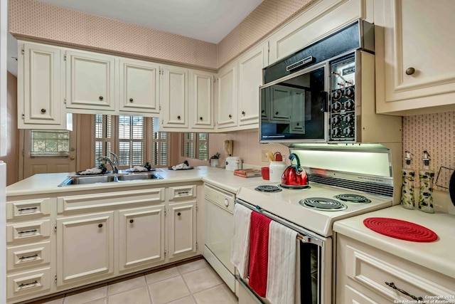 kitchen with white appliances, light tile patterned flooring, sink, and kitchen peninsula