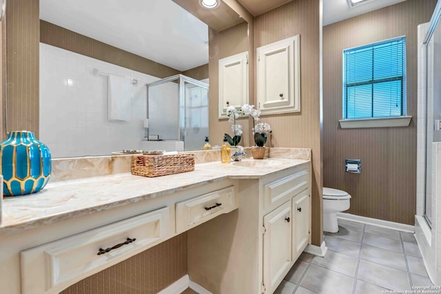 bathroom featuring tile patterned flooring, a shower with door, vanity, and toilet