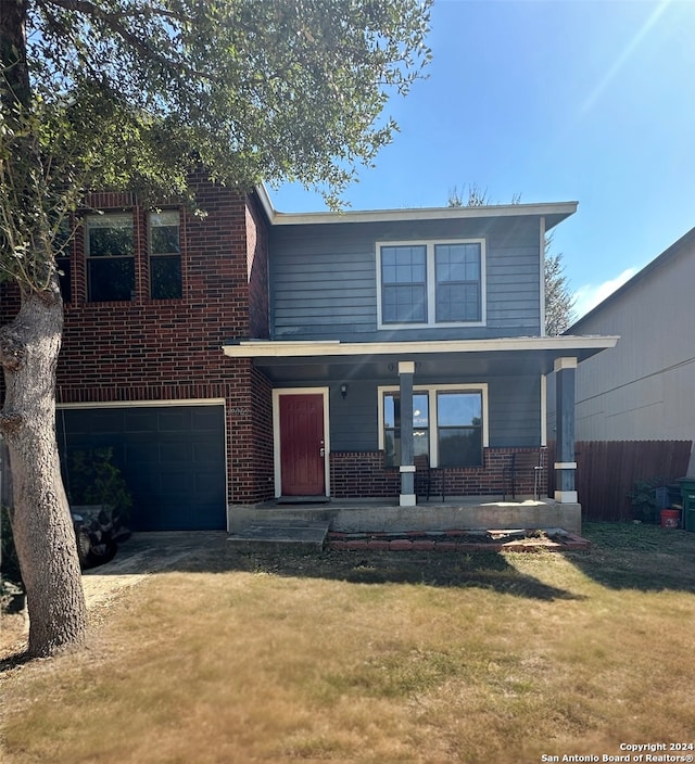 front of property featuring a front yard, a garage, and a porch