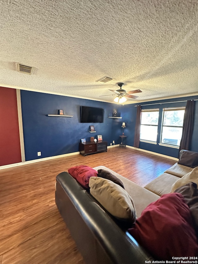 living room with a textured ceiling, wood-type flooring, and ceiling fan