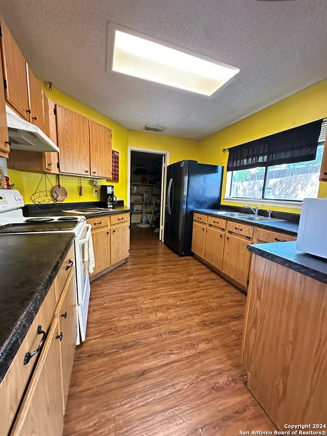 kitchen featuring light wood-type flooring, a textured ceiling, black fridge, sink, and white electric range