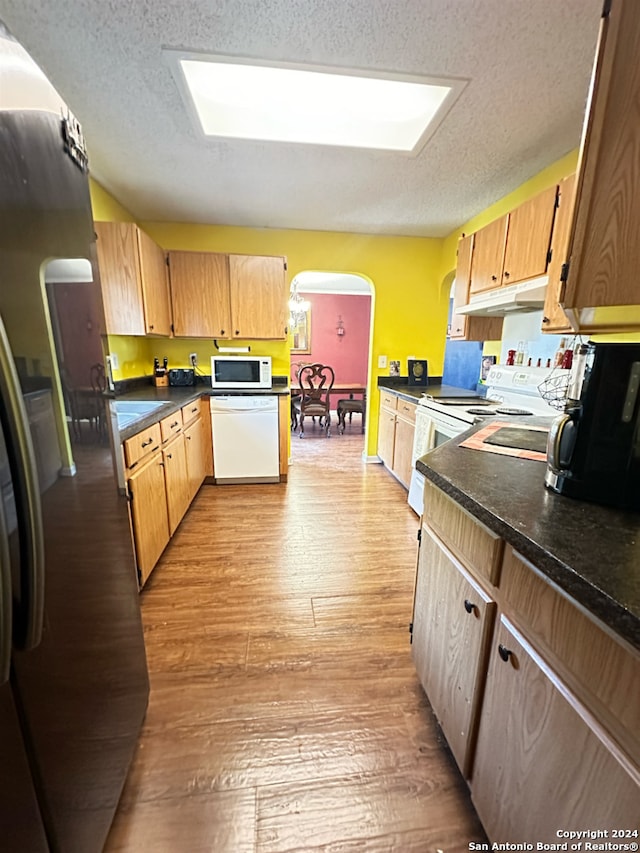 kitchen featuring a textured ceiling, white appliances, and light hardwood / wood-style flooring