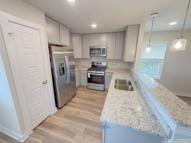 kitchen with pendant lighting, sink, light hardwood / wood-style flooring, stainless steel appliances, and light stone countertops