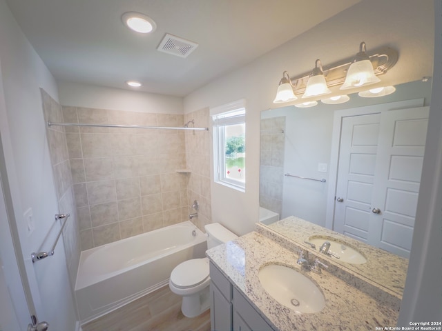 full bathroom featuring vanity, tiled shower / bath, hardwood / wood-style flooring, and toilet