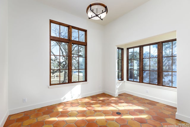 spare room featuring a chandelier and baseboards