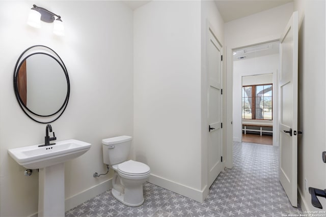 half bathroom with toilet, tile patterned floors, and baseboards