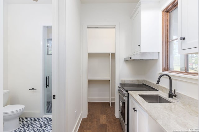 kitchen featuring stainless steel range with electric stovetop, a sink, light stone countertops, under cabinet range hood, and white cabinetry