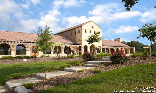 mediterranean / spanish-style house with a front yard and stone siding