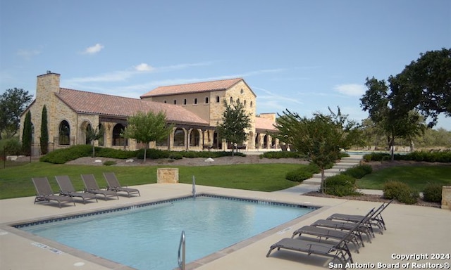 community pool with a patio and a yard