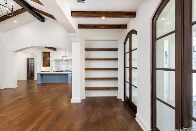 hall featuring dark wood finished floors, visible vents, arched walkways, and beamed ceiling