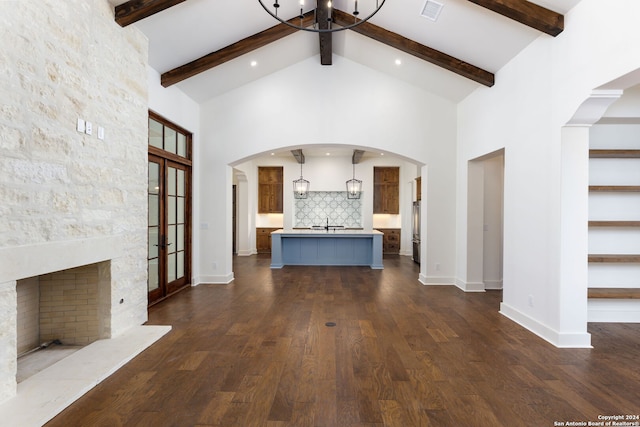 unfurnished living room with arched walkways, an inviting chandelier, a sink, visible vents, and high vaulted ceiling