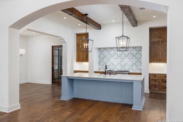 kitchen with dark wood finished floors, an island with sink, decorative backsplash, beam ceiling, and visible vents