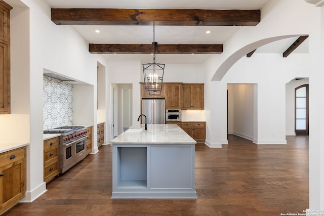 kitchen with pendant lighting, an island with sink, appliances with stainless steel finishes, and dark hardwood / wood-style flooring