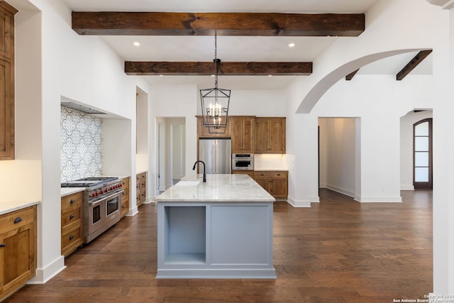 kitchen with brown cabinets, decorative backsplash, stainless steel appliances, arched walkways, and dark wood-style flooring
