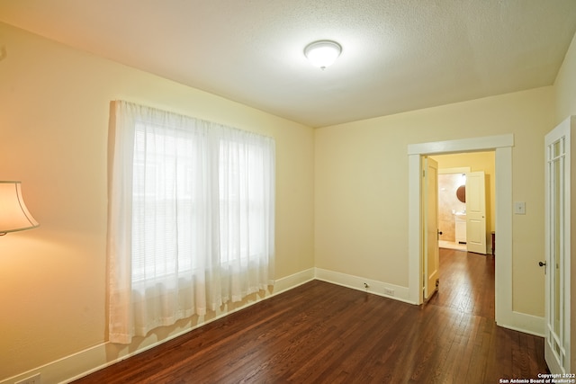 spare room with a textured ceiling and dark wood-type flooring