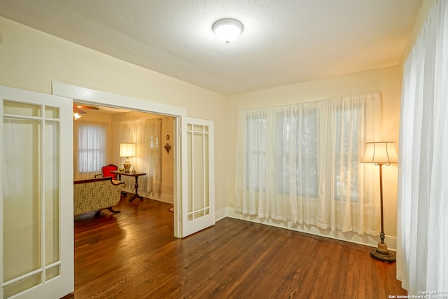 empty room with ceiling fan, a textured ceiling, hardwood / wood-style flooring, and french doors