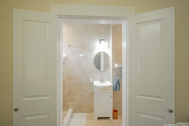 bathroom featuring a tile shower, vanity, tile walls, and tile patterned floors