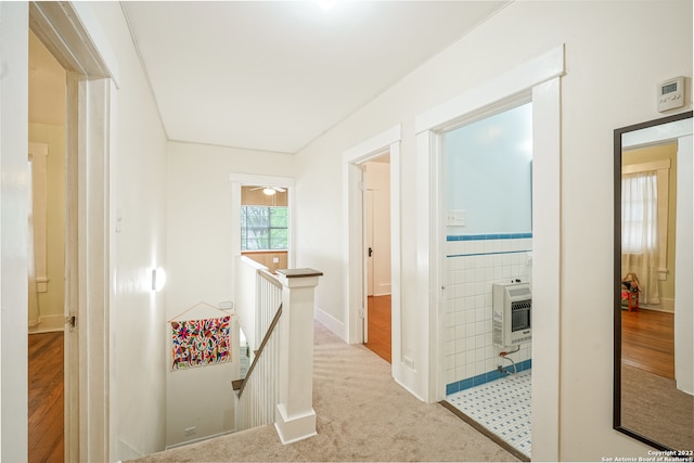 corridor featuring heating unit, tile walls, and light hardwood / wood-style floors