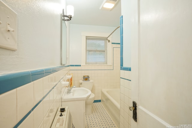 full bathroom featuring tiled shower / bath, vanity, toilet, tile walls, and tile patterned flooring