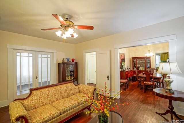 living room featuring ceiling fan with notable chandelier, dark wood-type flooring, and french doors