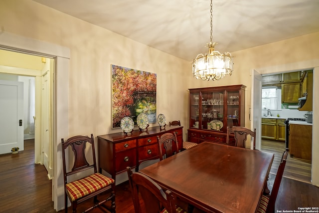 dining area with dark wood-type flooring and a notable chandelier