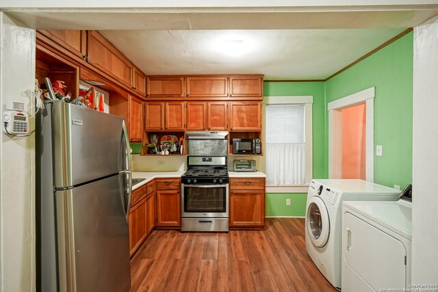 kitchen with wood-type flooring, appliances with stainless steel finishes, independent washer and dryer, and crown molding