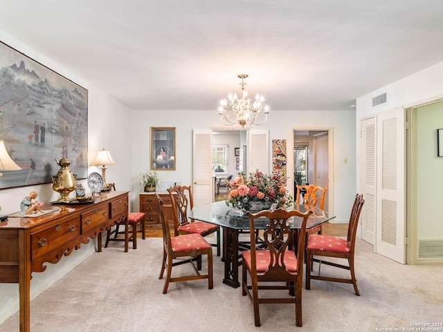 dining space with light carpet and a chandelier